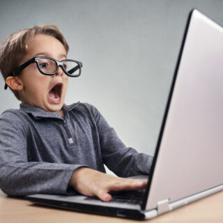 Shocked and surprised boy on the internet with laptop computer as he realizes just how little privacy there is on the web