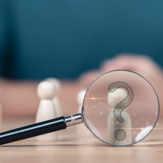 Photo artwork - little wooden figures with a magnifying glass focused on one
